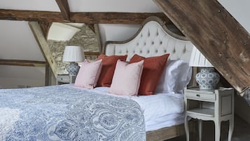 A bedroom with a bed, pillows, a nightstand, and a lamp.
