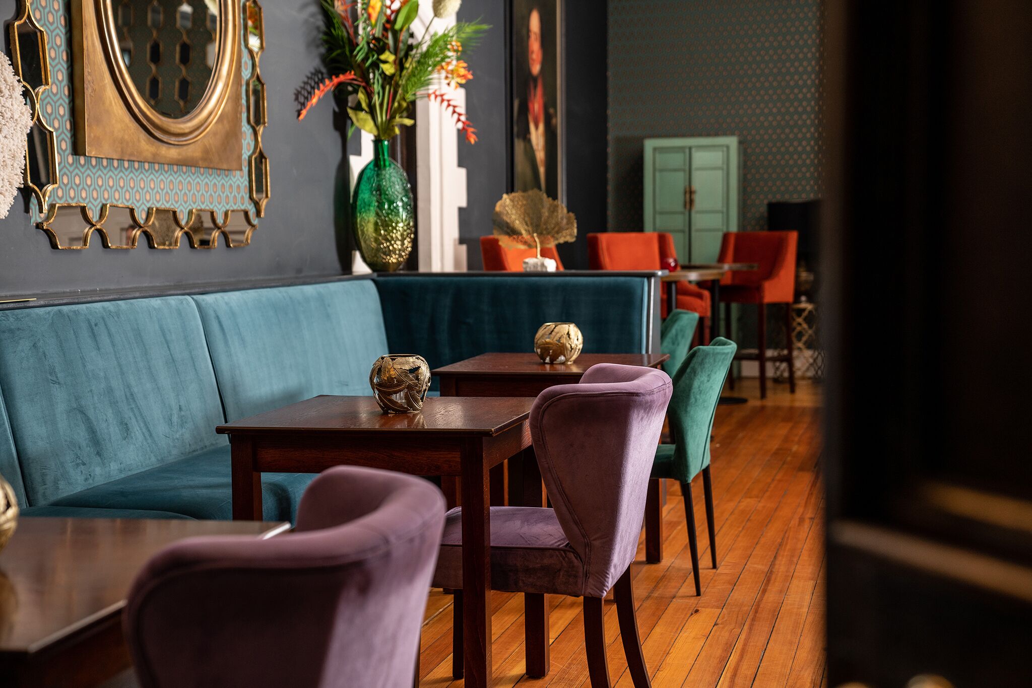 A dining area with a blue sofa, wooden tables, and purple chairs.