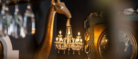 Un lustre à plusieurs lampes, une sculpture de girafe et un miroir orné d’un motif géométrique.
