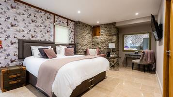 A bedroom with a large bed, a suitcase, a desk, and a chair.