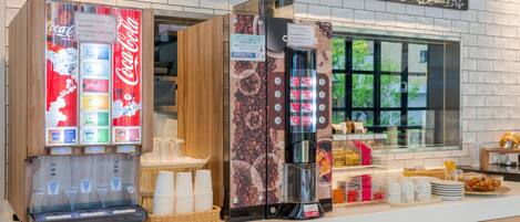 Una estación de café con una máquina de Coca-Cola, un dispensador de café y un menú en una pizarra.
