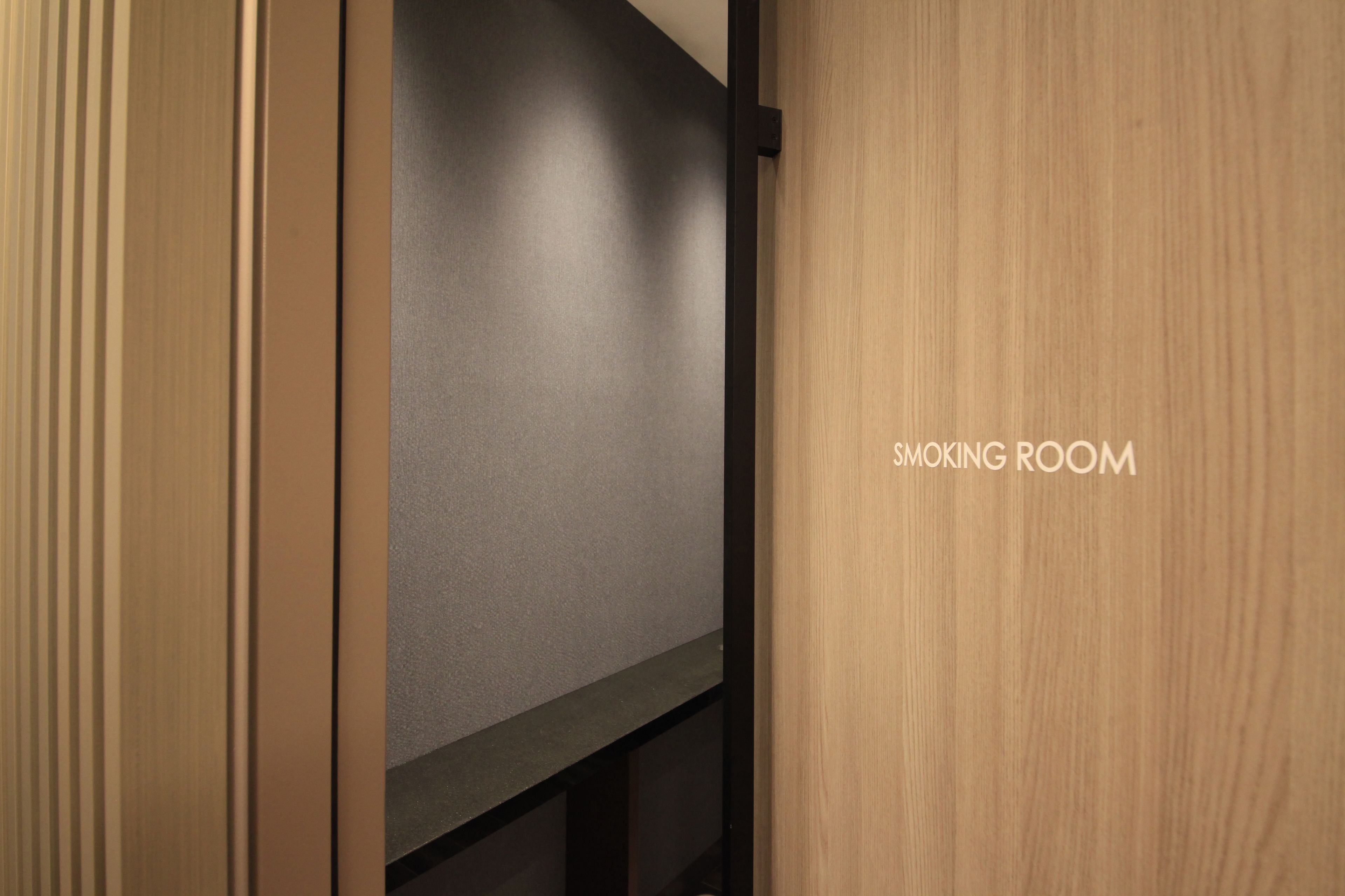 A doorway leading to a room labeled "SMOKING ROOM" with a wooden door and a grey wall.