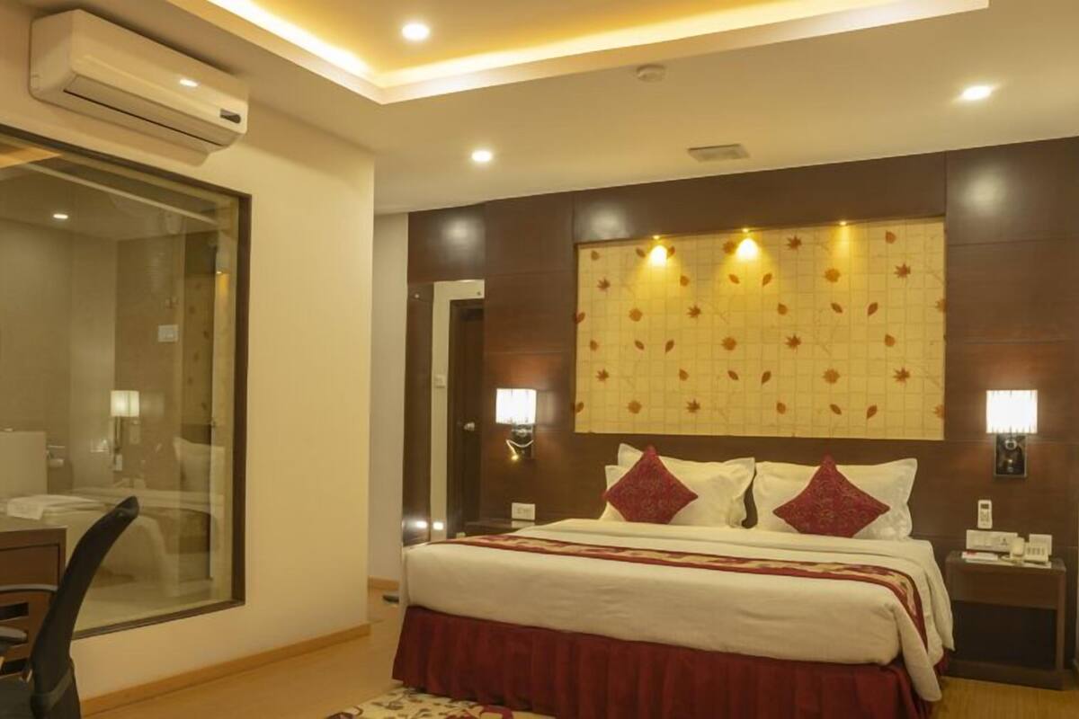 A hotel room with a bed, bedside table, lamp, and a desk with a chair.