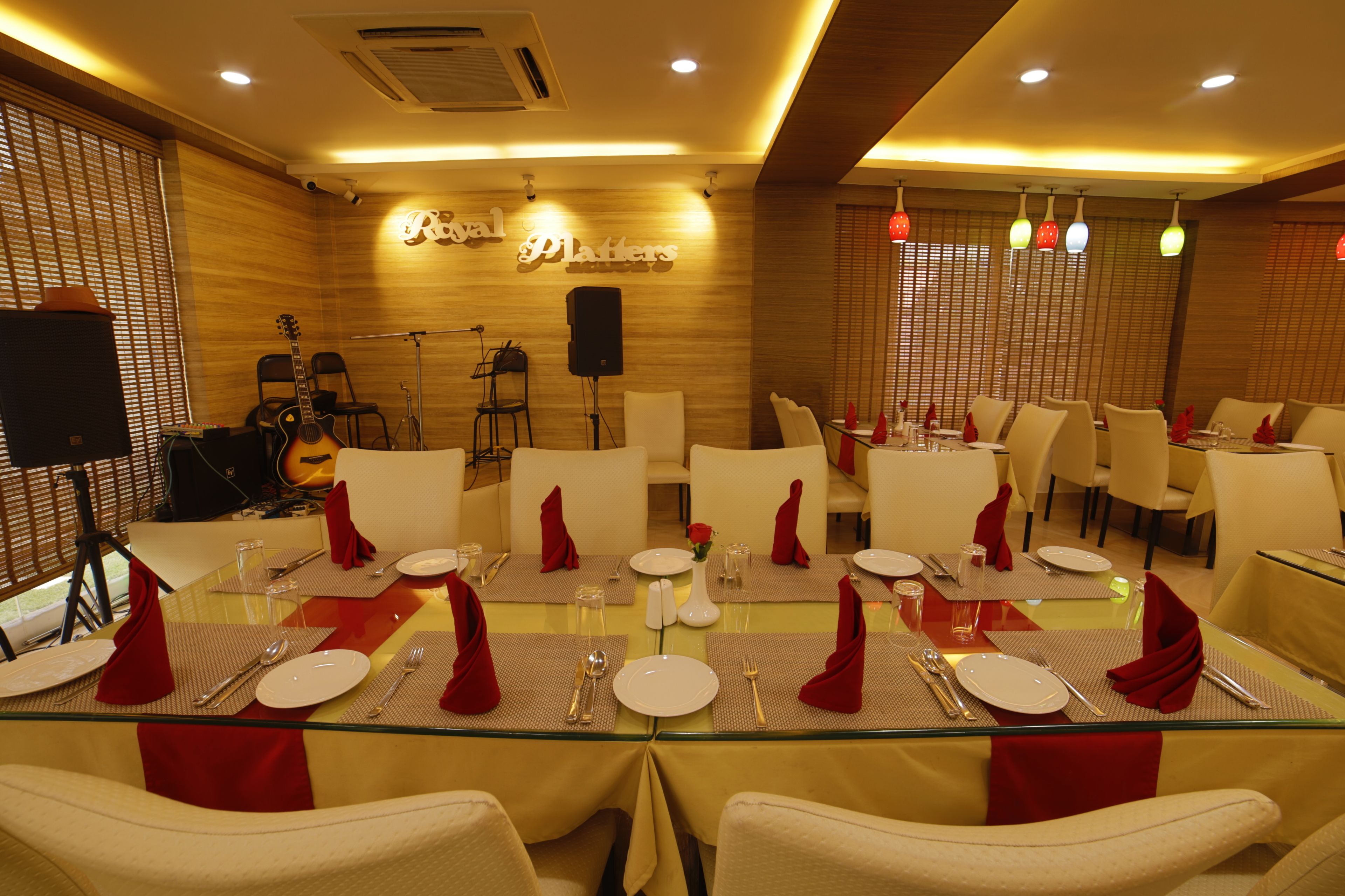 Un comedor con mesas dispuestas para el servicio, un escenario con instrumentos musicales y un letrero que dice "Royal Planners".