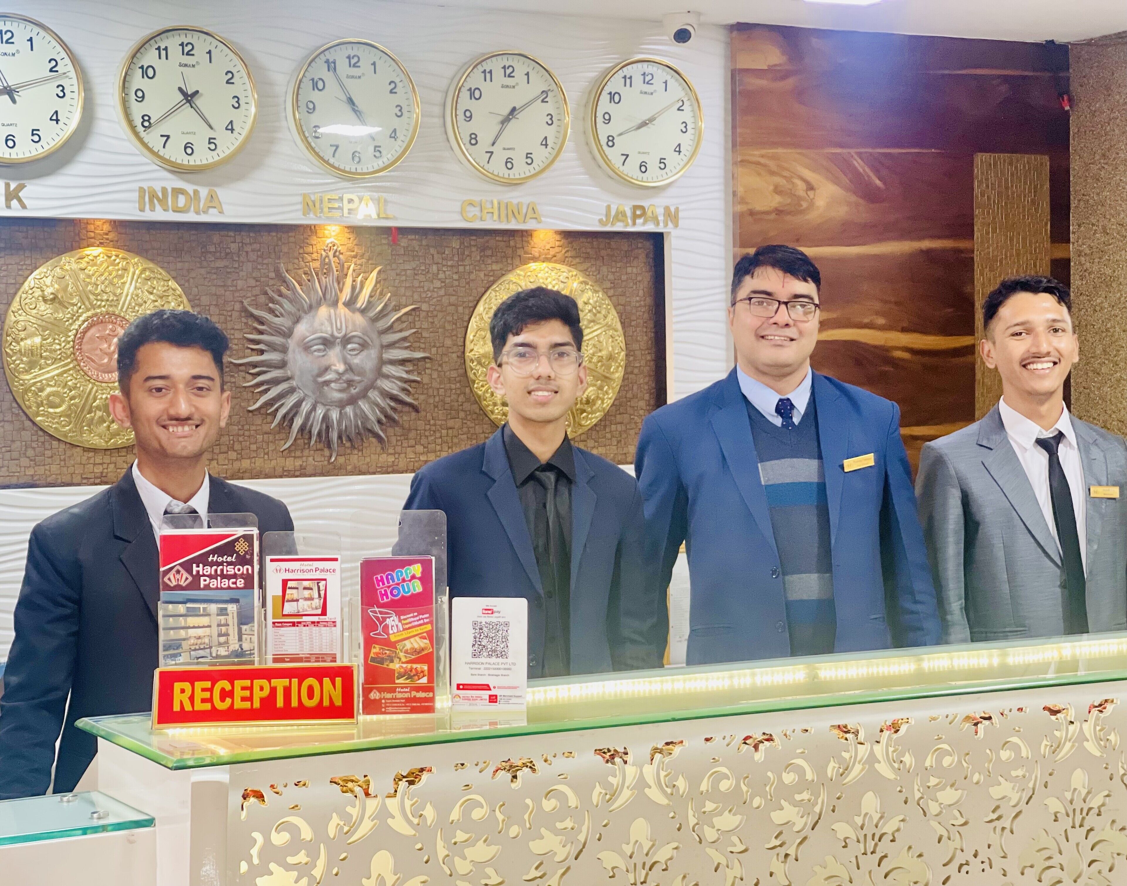 A reception desk with clocks displaying times for India, Nepal, China, and Japan.