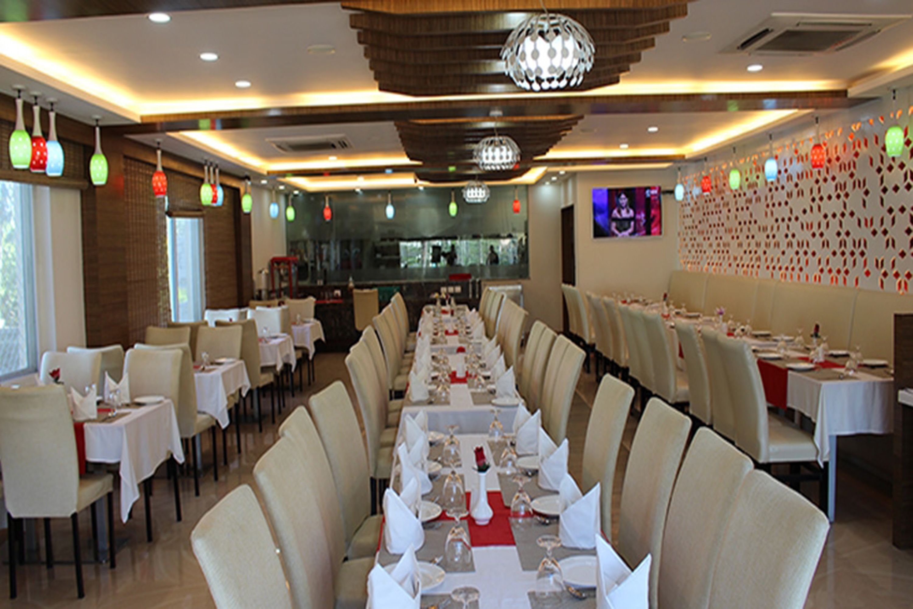 A restaurant with a long dining table set for a meal, surrounded by chairs.