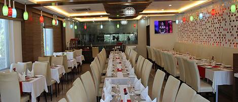 A restaurant with a long dining table set for a meal, surrounded by chairs.