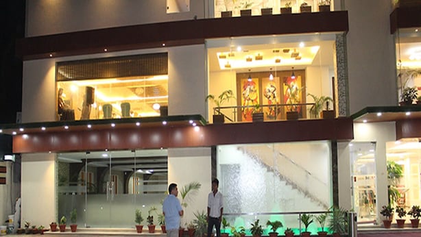 A hotel entrance with a glass facade, potted plants, and a staircase leading to the upper level. - Hotel Harrison Palace (Biratnagar)
