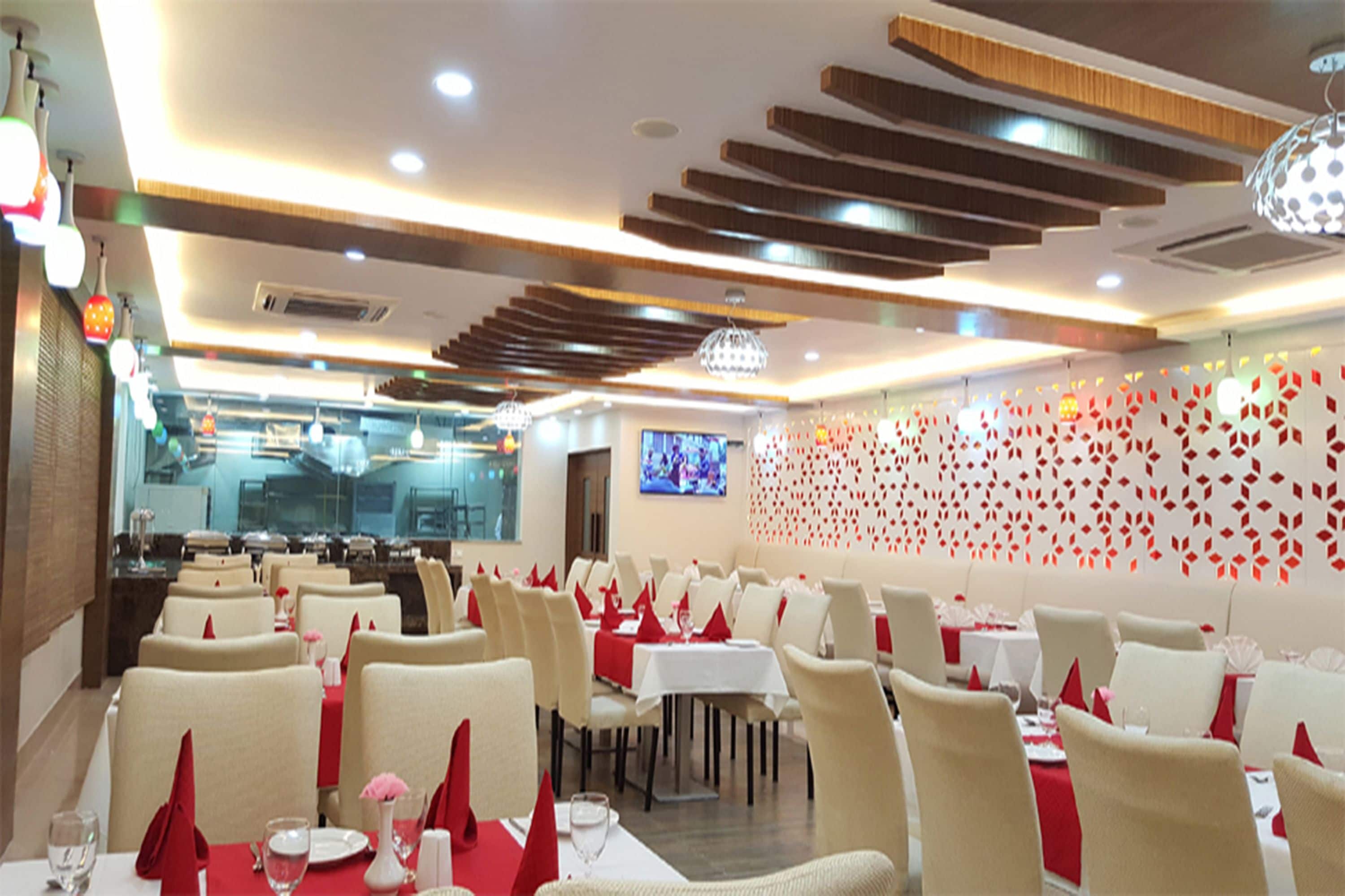 A restaurant with multiple dining tables, chairs, and a television screen on the wall.