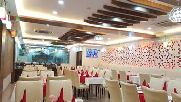 A restaurant with multiple dining tables, chairs, and a television screen on the wall.