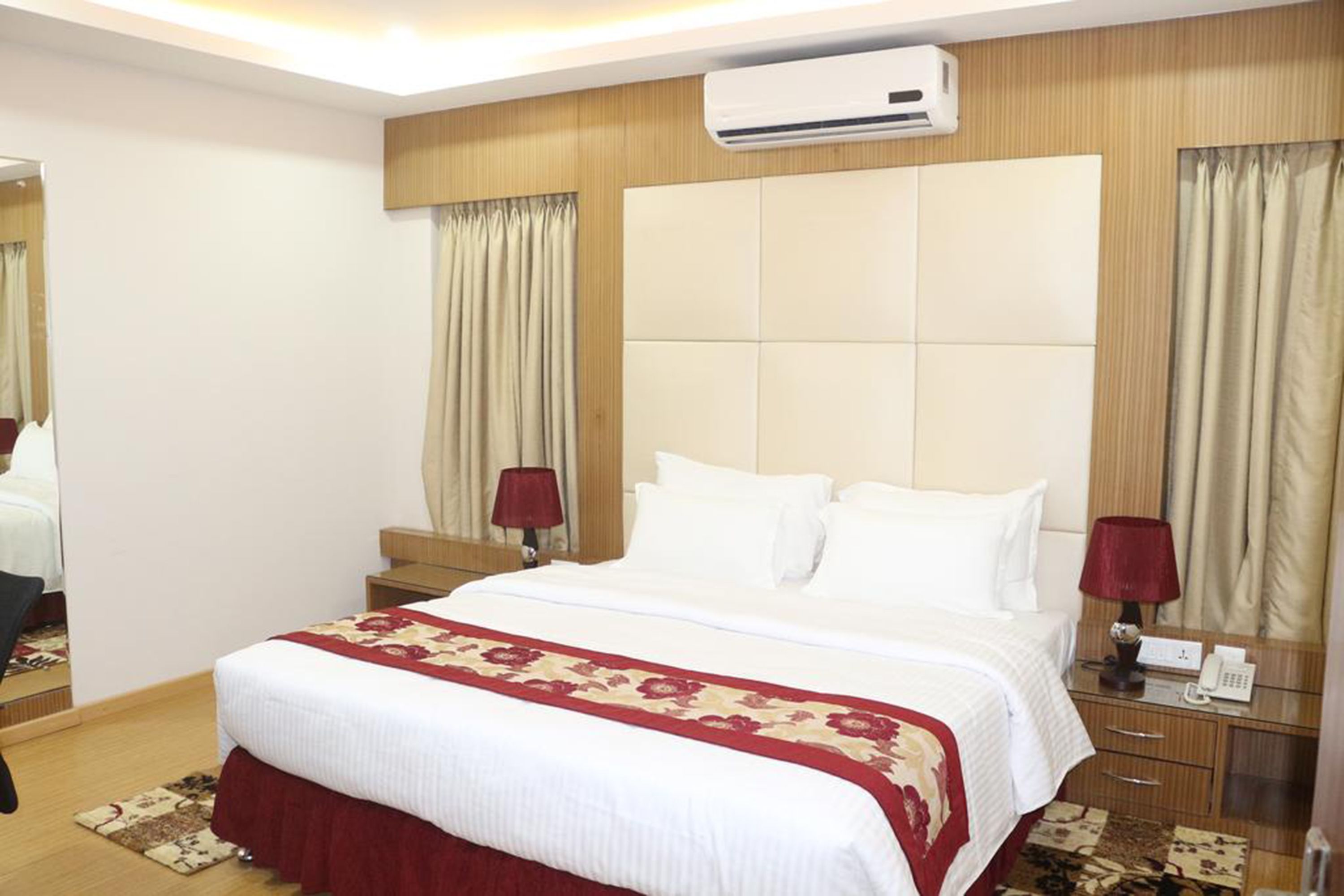 Une chambre d’hôtel avec un grand lit, une table de chevet avec une lampe, un appareil de climatisation et un téléphone.