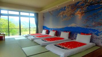 Une chambre avec trois lits alignés le long d’un mur orné d’une fresque représentant le mont Fuji.