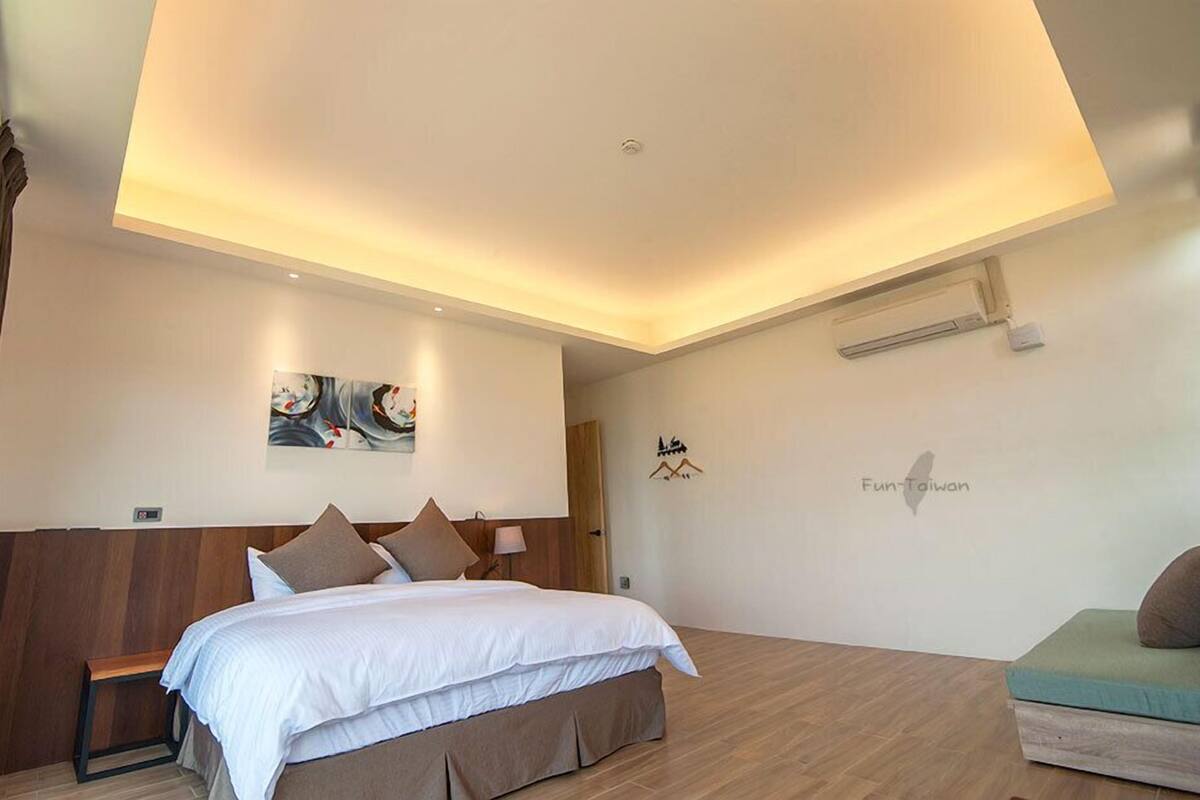 A modern bedroom with a bed, bedside tables, a bench, and a sofa.