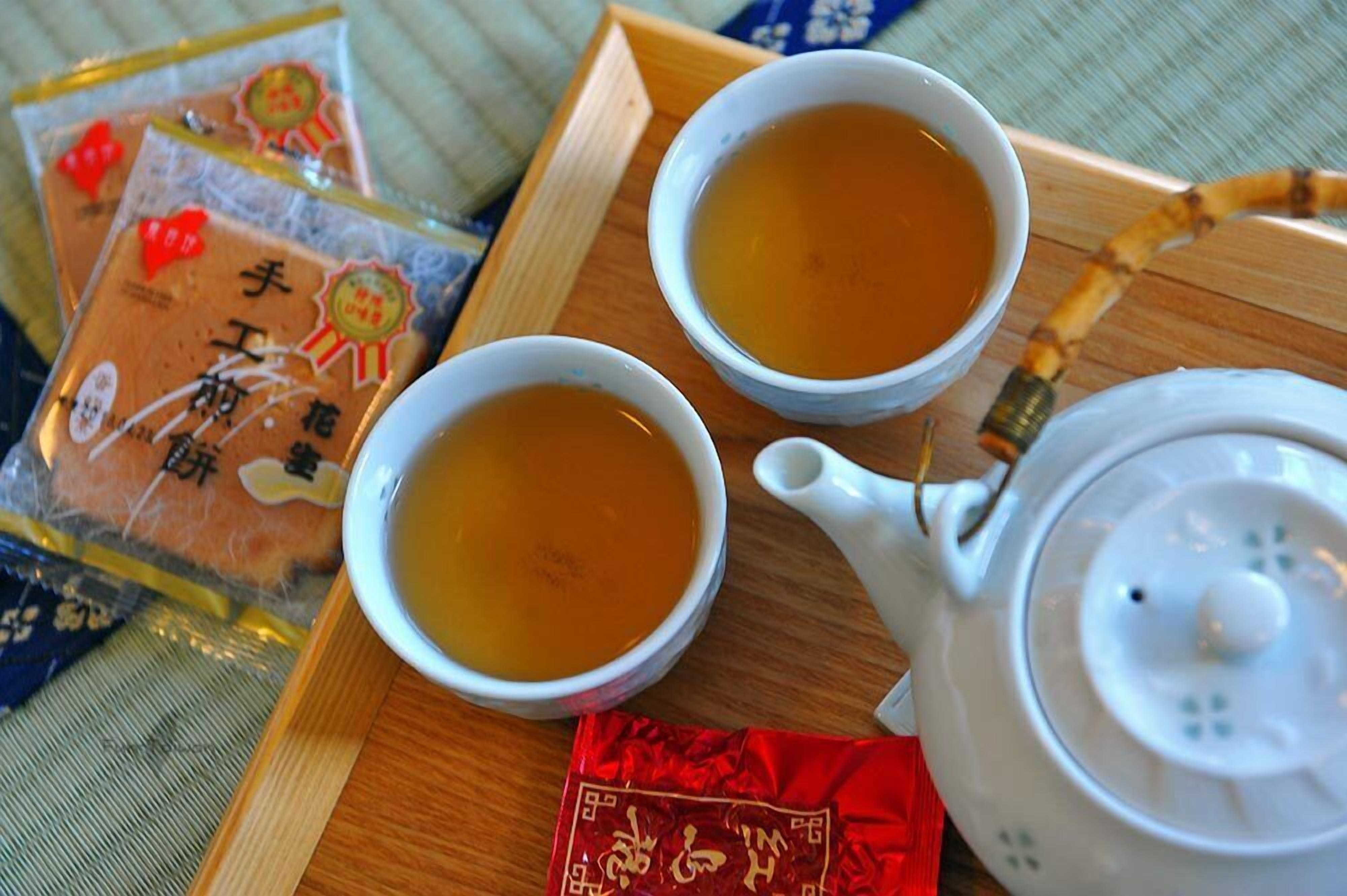 Two cups of tea on a tray with a teapot and tea bags.