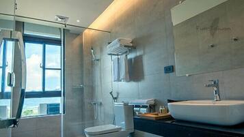 A modern bathroom with a large window, a walk-in shower, a toilet, and a sink.
