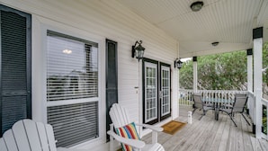A covered porch with white wooden railings, a table with chairs, and two Adirondack chairs with colorful cushions. - 30A Beach House - Walking on Sunshine by Panhandle Getaways (Panama City Beach)