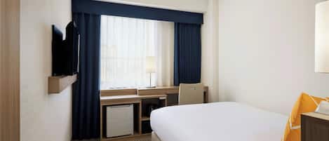 Una habitación de hotel con cama, escritorio, televisor y ventana con cortinas.