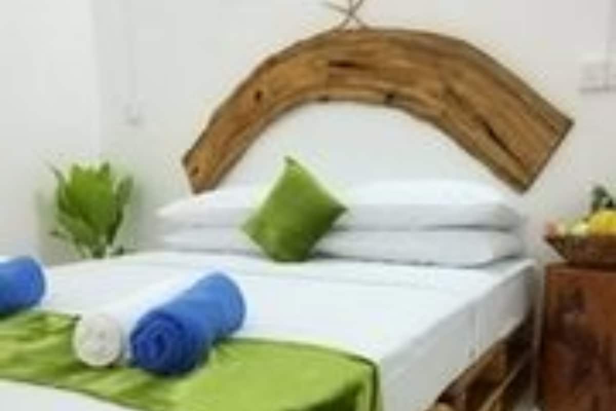 A bed with a wooden headboard, a green pillow, and rolled blue towels.
