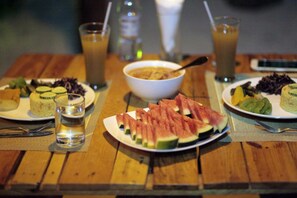 Une table en bois avec des assiettes remplies de nourriture, un bol de soupe et des verres contenant des boissons.