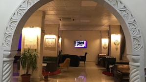 Un vestíbulo con televisor, zona de estar y arcos decorativos.
