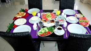 Una mesa de comedor lista para el desayuno, con platos, vasos y diversas opciones de comida.