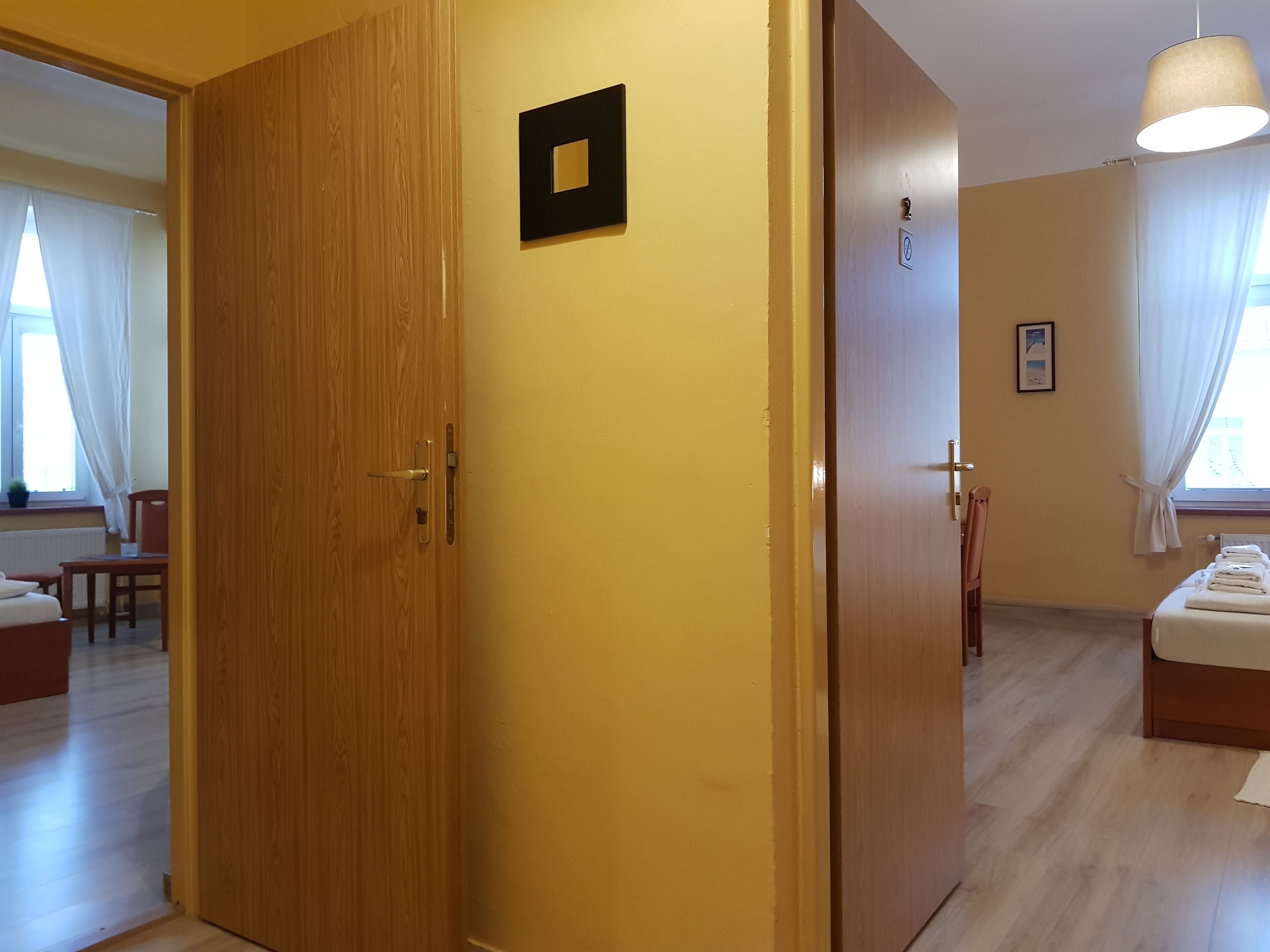 Una habitación de hotel con un armario de madera, una cama con ropa blanca, una mesita pequeña y una silla.