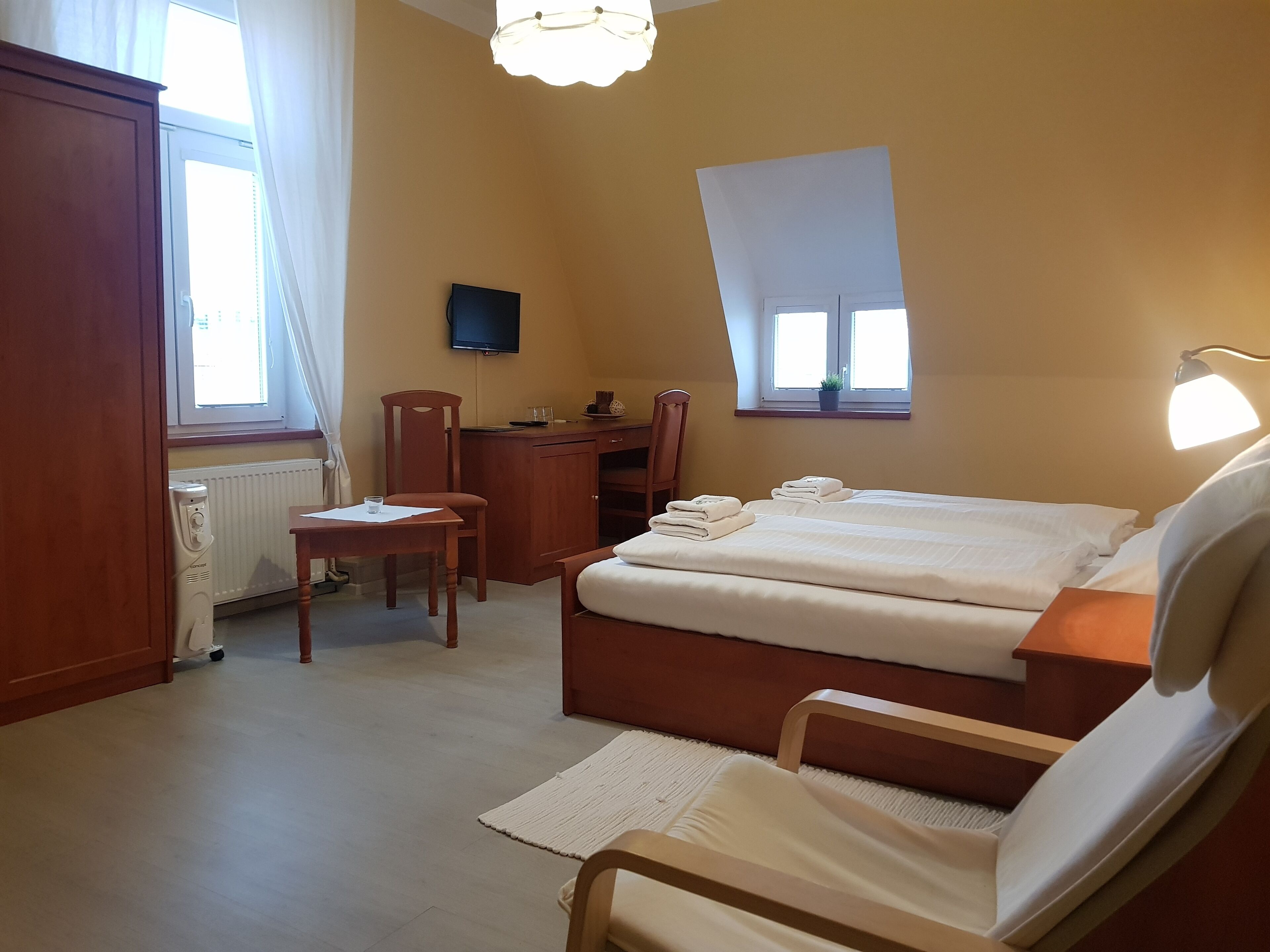 A hotel room with a bed, a desk, a chair, a TV, and a window.