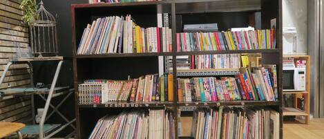 Una estantería llena de libros en una habitación con suelo de madera y un estante de metal.