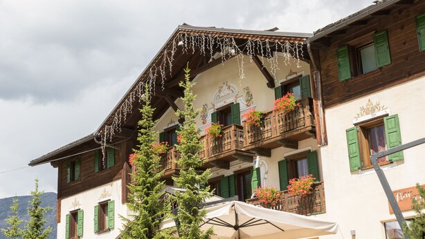 Un chalet traditionnel doté de balcons, avec une vue sur les montagnes et un espace extérieur aménagé pour s’asseoir.