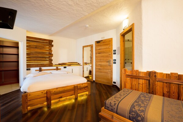 A room with a wooden bed, a wooden bench, and a wooden wall panel. - Hotel Pontiglia (Livigno)