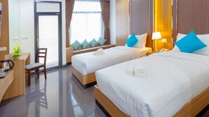 Habitación de hotel con dos camas, un escritorio con silla, una mesita con una planta y una ventana con cortinas.