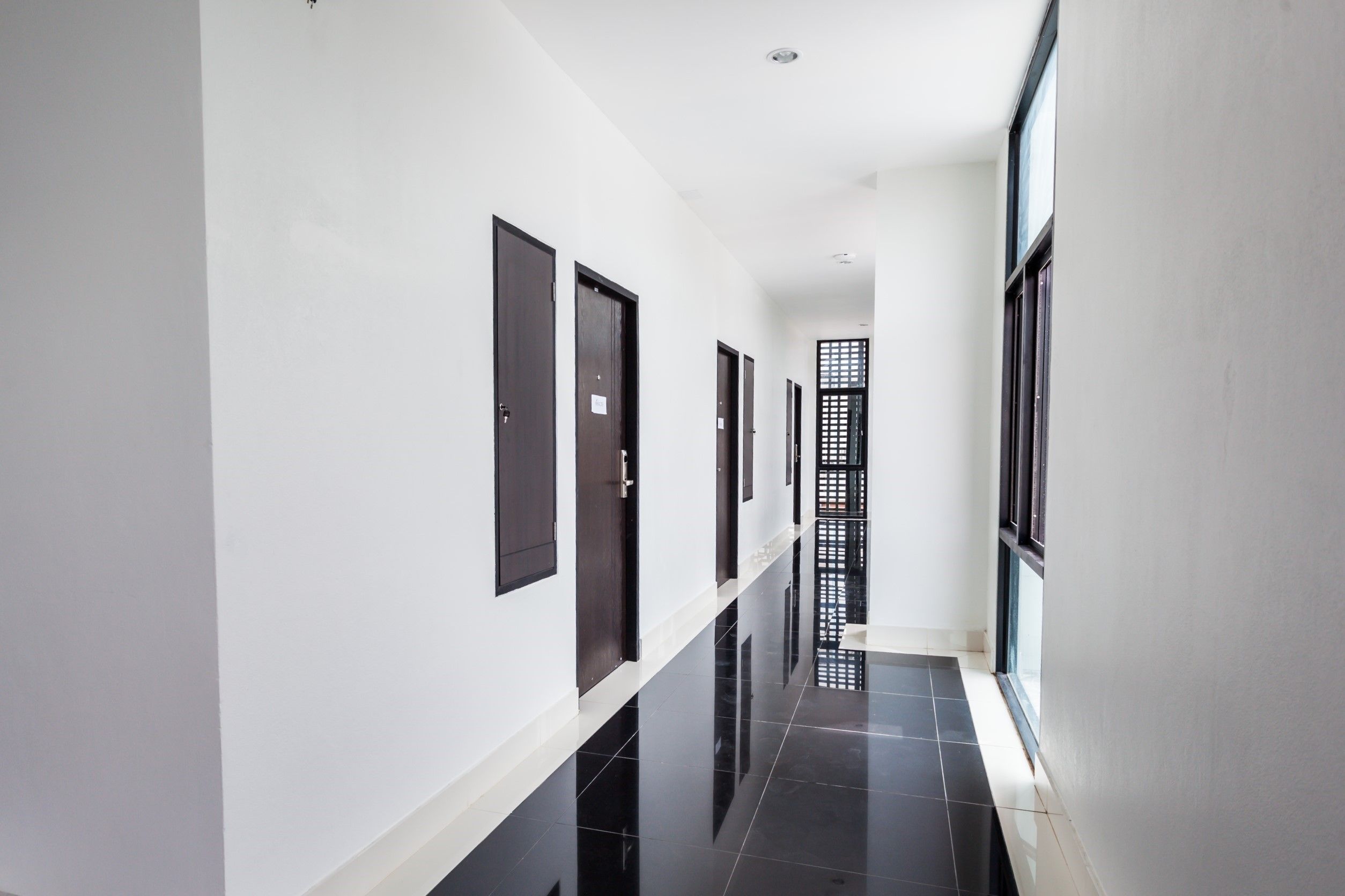 A long, narrow hallway with white walls and black-tiled floors.