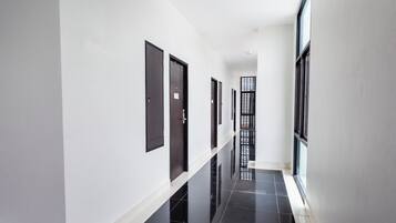 A long, narrow hallway with white walls and black-tiled floors.