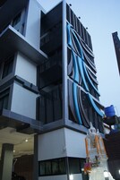 Un edificio moderno con una fachada distintiva que presenta patrones azules y blancos, un depósito de agua destacado y una estructura decorativa con flores.