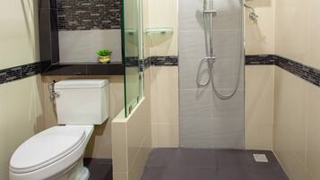 A bathroom with a toilet, a glass shower enclosure, and a tiled floor.