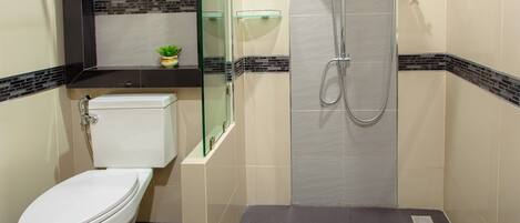 A bathroom with a toilet, a glass shower enclosure, and a tiled floor.