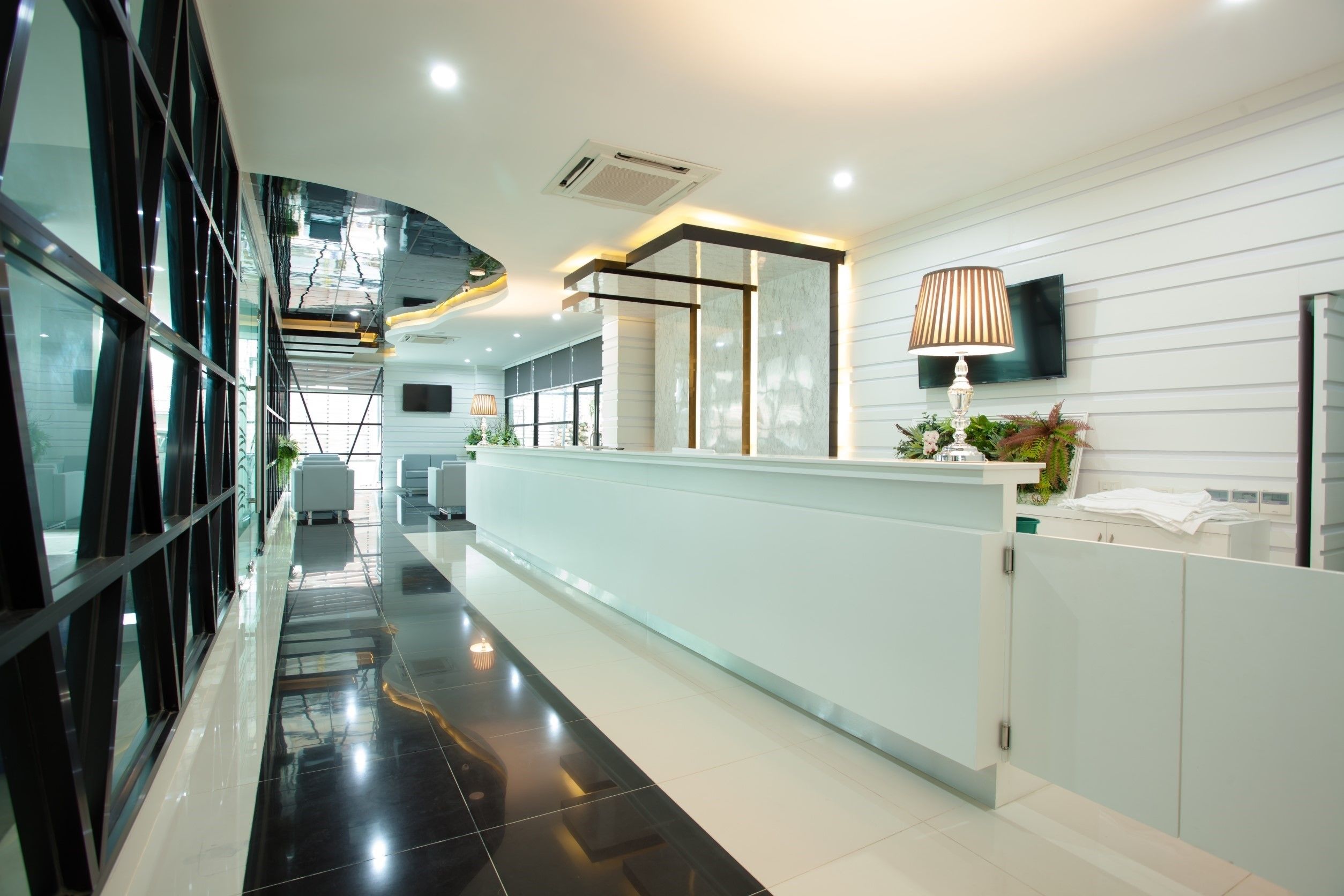 A modern reception area with a glass wall, a reception desk, and a mounted TV.