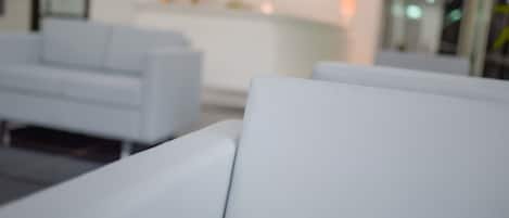 Un moderno vestíbulo de hotel con sofás blancos y una zona de recepción al fondo.
