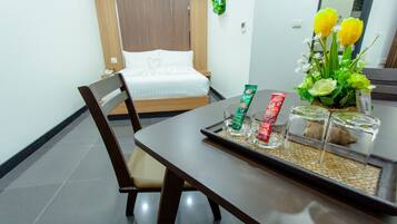 A hotel room with a bed, a dining table with a tray, and a vase with flowers.