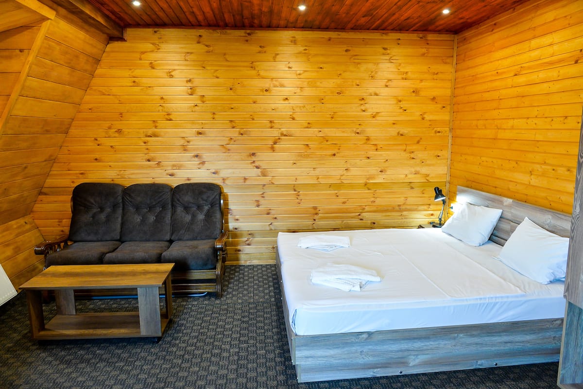 A wooden-paneled room with a bed, a sofa, and a small table.