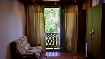 A room with a wooden bench, a red rug, a wardrobe, and a view through a window with curtains.