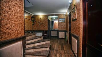 Una escalera de madera que lleva a un rellano con un muro estampado y un cuadro enmarcado.
