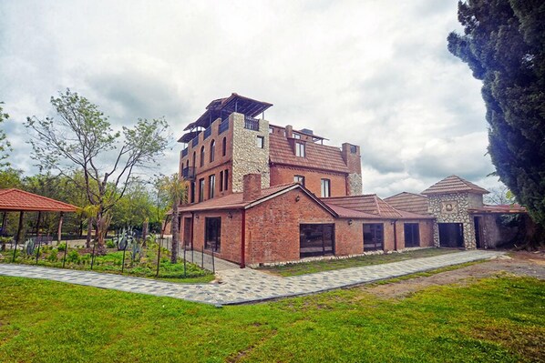 A multi-story building with a mix of brick and stone construction, featuring a prominent tower and a covered patio area.