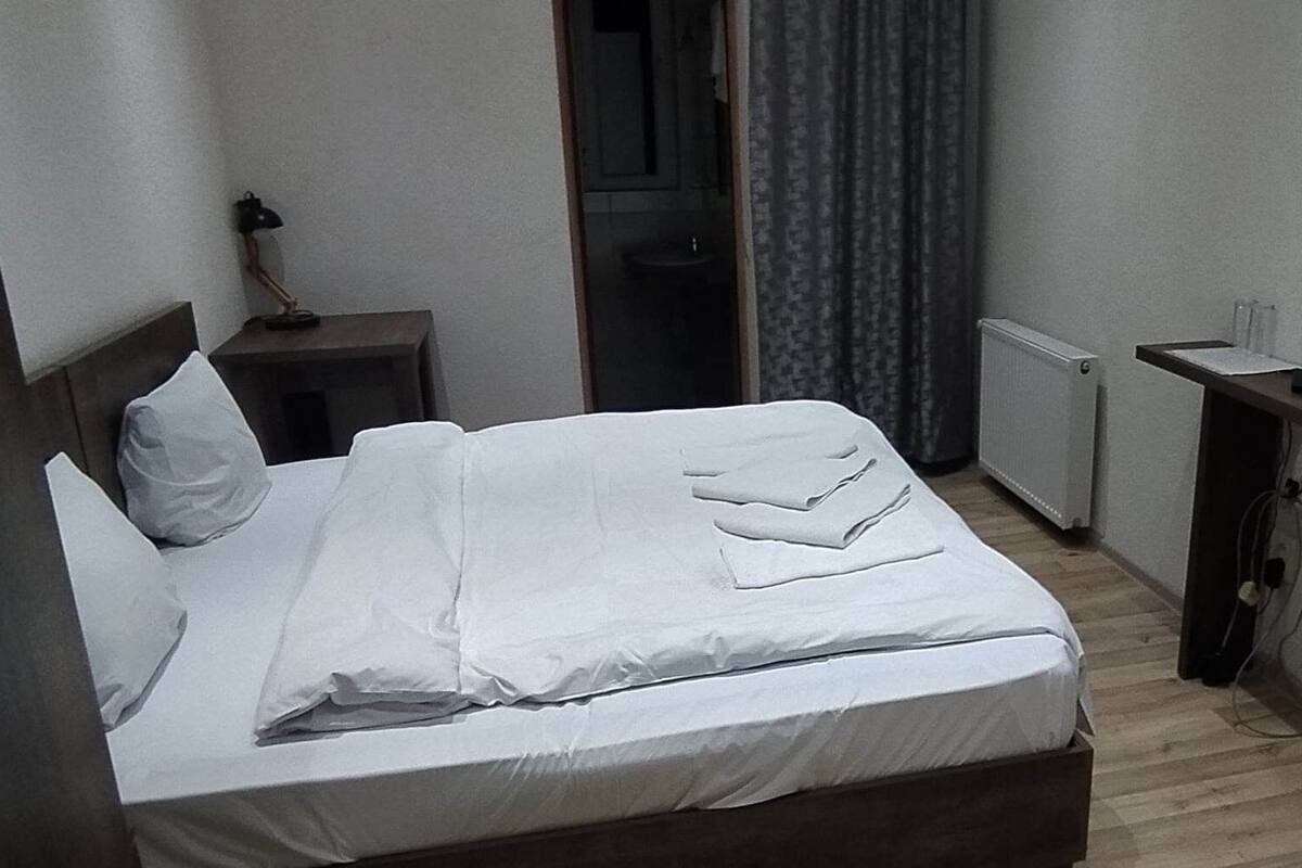 A hotel room with a bed, a desk, a TV, and a window with curtains.