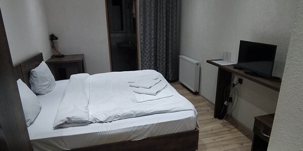 A hotel room with a bed, a desk, a TV, and a window with curtains. - Chateau Chikovani (Khoni)