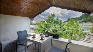 Un espacio de estar techado al aire libre con una mesa y sillas, que ofrece vistas panorámicas del agua y la vegetación.