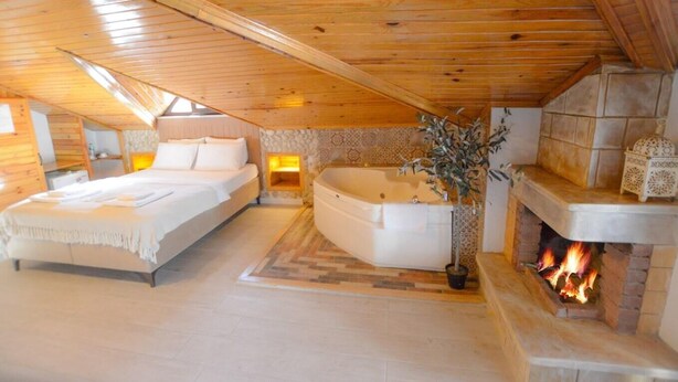Un dormitorio acogedor con una cama grande, un rincón de descanso, una bañera y una chimenea.