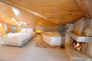 A cozy bedroom with a large bed, a sitting area, a bathtub, and a fireplace. - Agva Piassa Otel (Sile)