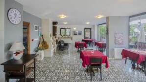 Un restaurante con suelo de baldosas, manteles rojos y un reloj en la pared.