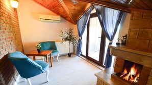 Una habitación acogedora con chimenea, un sofá, una mesa y una planta en maceta.